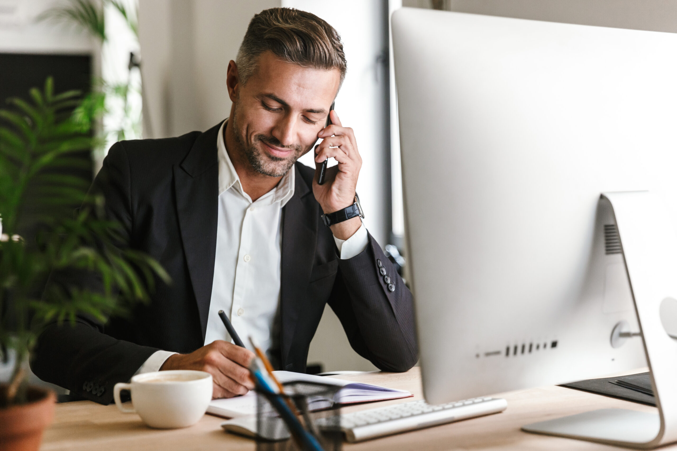 Image of handsome businessman talking on cell phone while workin